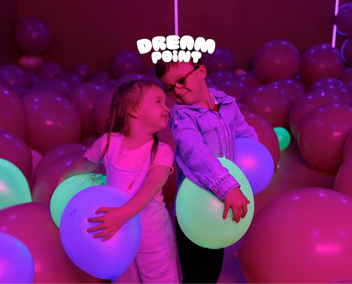 Two children smiling inside the glowing Dream Point Experience