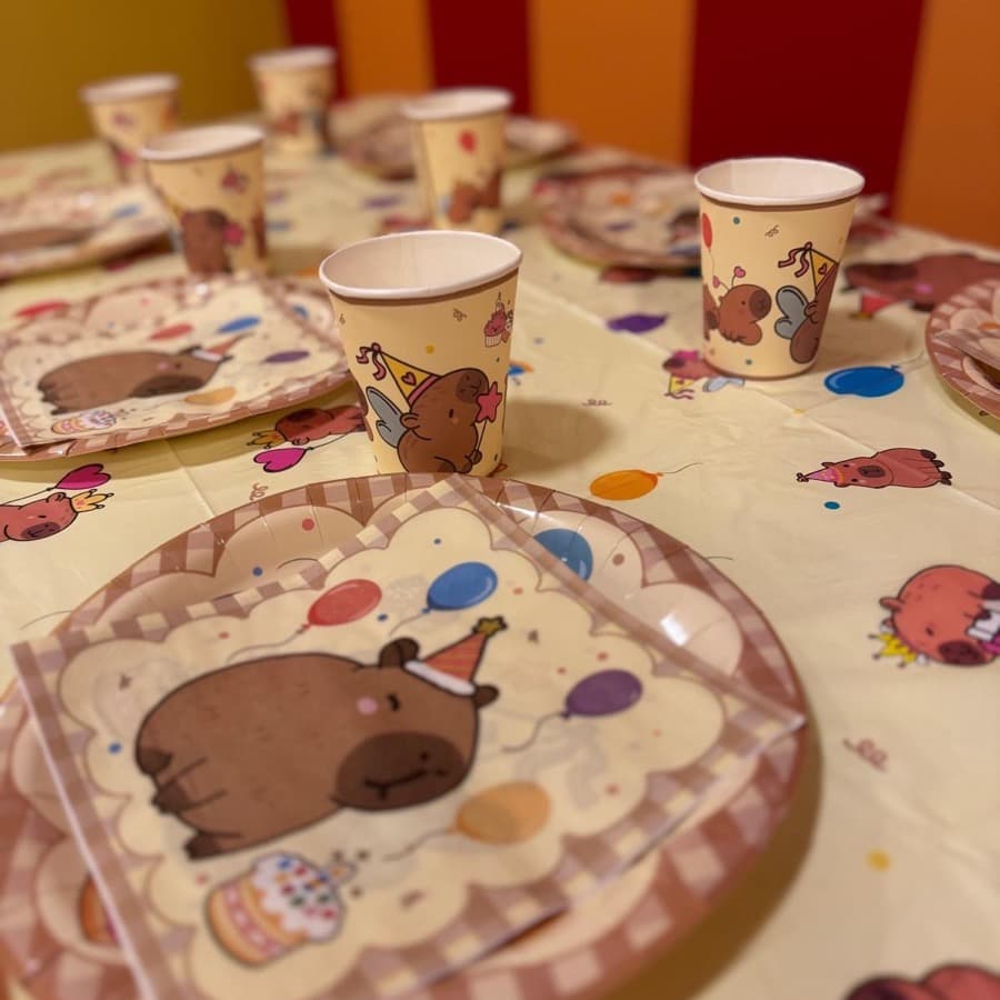A party table set with capybara themed plates, cups and napkins