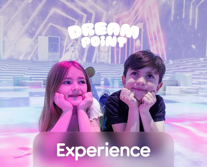 Two children smiling inside the glowing Dream Point experience